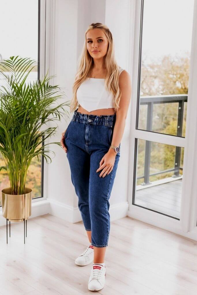 Model styling the versatile White Corset Top paired with comfortable paperbag jeans for a chic look.