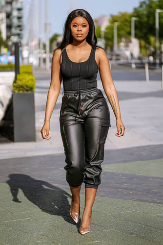 Our model showcasing the Black Faux Leather Cargo Pants. Pair them with heels or trainers, and you&#39;re ready to take on the day.